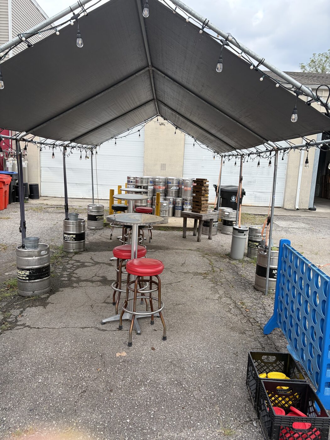 Covered patio with keg-barrel tables and string lights